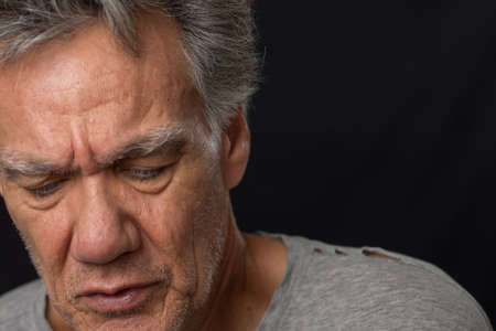 Distraught unshaven senior man at home looking depressed and tired of being locked downの写真素材