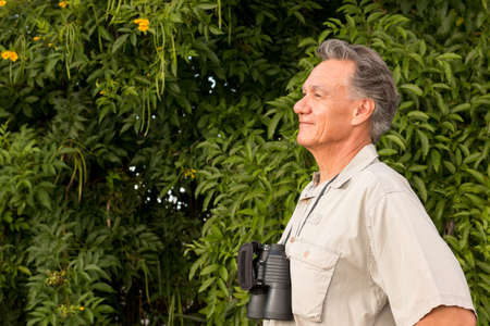 Senior Man outside enjoying nature looking through binocularsの写真素材