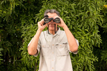 Senior Man outside enjoying nature looking through binocularsの写真素材