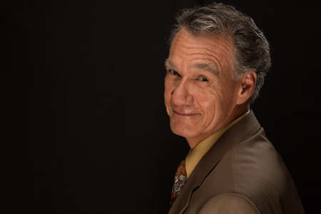 Portrait of a Mature Business Man Wearing a Tie and Jacket against a Black Background