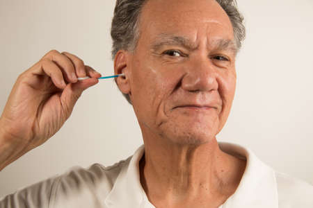 Senior Man Cleaning his Ears with a Cotton Tip Swab