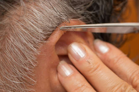 Senior Man getting his hair trimmed around the ear
