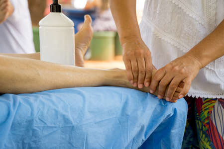 Massage Therapist Massaging a Womenâs Foot at an Outdoor Parkの写真素材