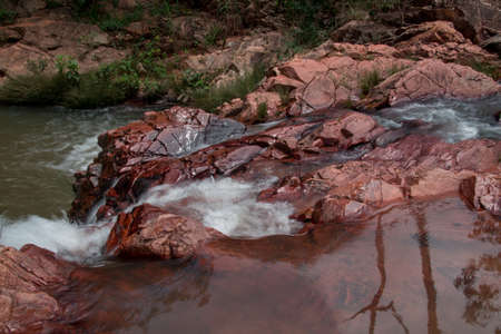 Water Rushing Down a Stream over Red Rocks near Sao Joao da AlianÃ§a, Brazilの写真素材