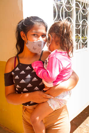 Planaltina, Goias, Brazil November 29 2020 : Young  mother with her child wearing a protective masks while waiting for food at a local feeding centerのeditorial素材