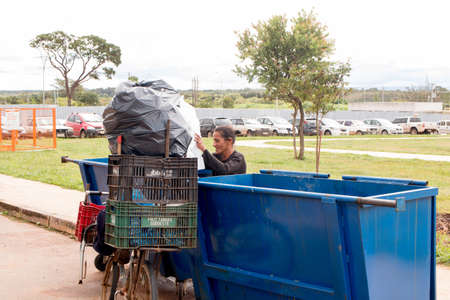 Brasilia, Brazil-March 27, 2020: A Poor Homeless Indigenous Woman Picking through the Trash to find...