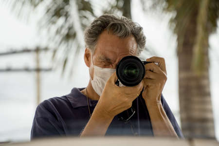 A photographer wearing a protective  face mask in public while taking photosの写真素材