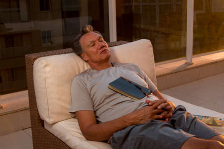 Man taking a nap on his balcony after reading a book