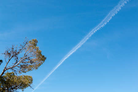 Chemtrails or Contrials high above the sky visible on a clear blue day