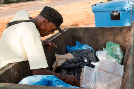 Brasilia, Brazil, September 30, 2019: A homeless man digging through the trash looking for...