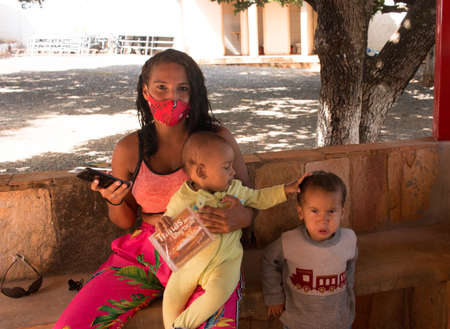 Planaltina Goias, Brazil-May 22, 2021: A young woman with her two children wearing protective masks at a food distribution center for the poor of the communityのeditorial素材