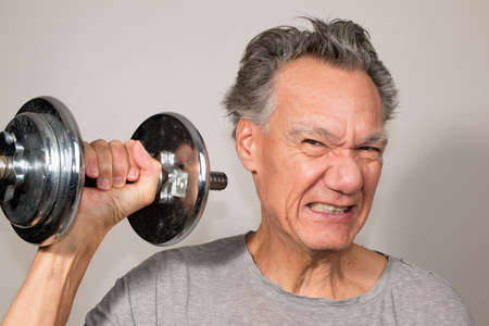 Fit Senior Man at Home Working out with Weights against a White Background