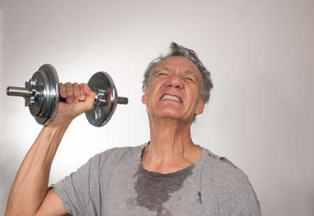 Fit Senior Man at Home Working out with Weights against a White Backgroundの写真素材