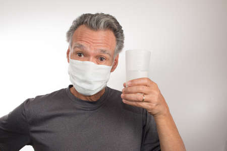Senior Man trying to Drink Water while still wearing his Surgical Mask
