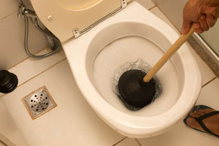 Man Using Plunger to unstop his toiletの写真素材