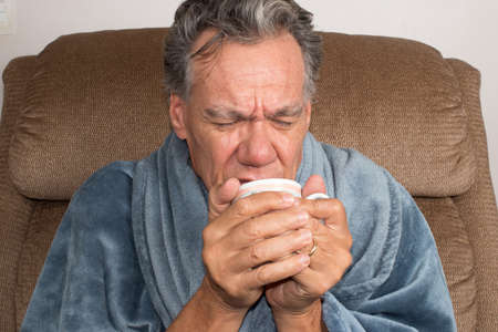 Mature Man not Feeling Well Wrap in a Blanket Drinking Tea