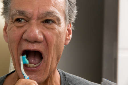 Mature Man Brushing his teeth with a Worn out Tooth Brushの写真素材