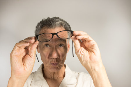 Mature man cleaning and checking his eye glasses to see if there cleanの写真素材