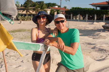 Mature couple at the beach in Combuco, Brazil, leaning against a small fishing boatの写真素材