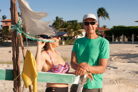 Mature couple at the beach in Combuco, Brazil, leaning against a small fishing boatの写真素材