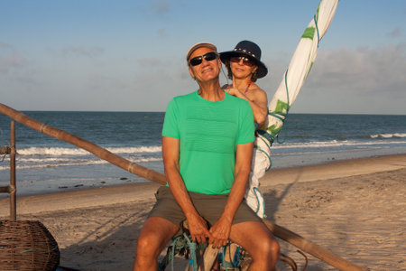 Mature couple at the beach in Combuco, Brazil, sitting on a Jangada a fishing boat typical in Brazilの写真素材