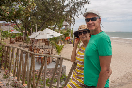 Mature couple at the beach in Combuco, Brazil, leaning against a wooden railの写真素材