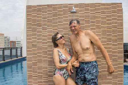 Couple rinsing off in an outdoor shower by the swimming poolの写真素材