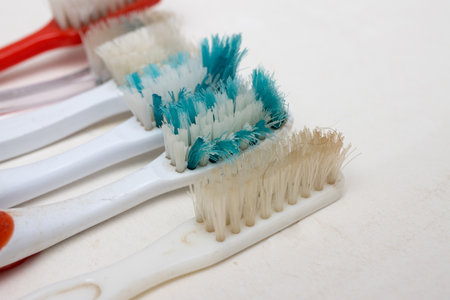 A bunch of old worn out toothbrushes with bent bristles on a white backgroundの写真素材
