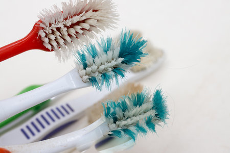 A bunch of old worn out toothbrushes with bent bristles on a white backgroundの写真素材