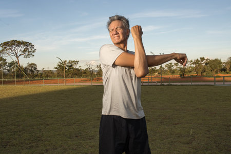 Mature Man outside on the grass doing Stretches before working outの写真素材