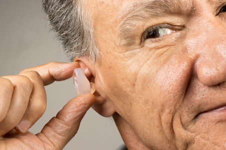 Older Man using custom made silicone earplugs for hearing protectionの写真素材