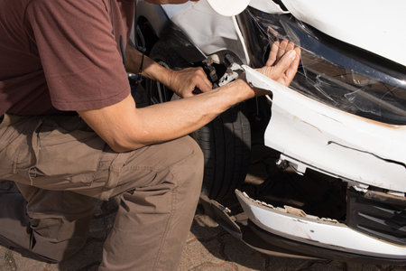 Man checking out the damage to the right front end of his car that was in a collisionの写真素材