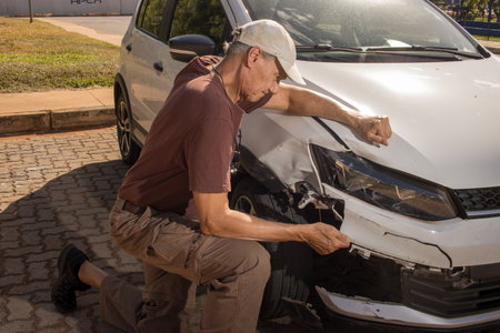 Man checking out the damage to the right front end of his car that was in a collisionの写真素材