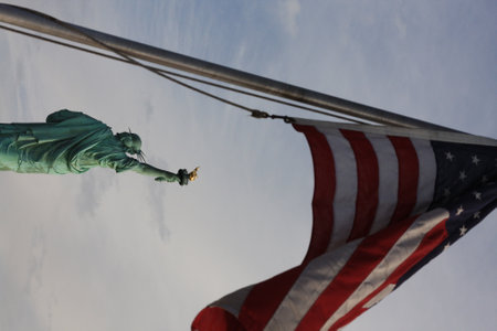 View of the Statue of Liberty with the American flag in the foregroundの写真素材