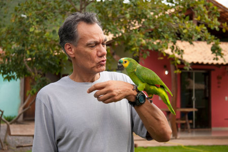 Man outside holding and playing with his Blue Fronted Amazon Parrotの写真素材