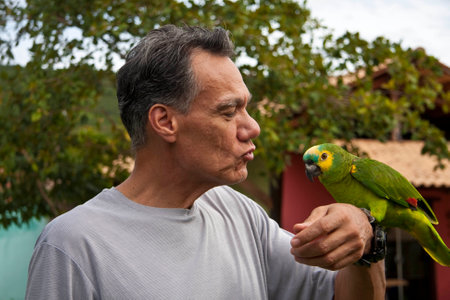Man outside holding and playing with his Blue Fronted Amazon Parrotの写真素材