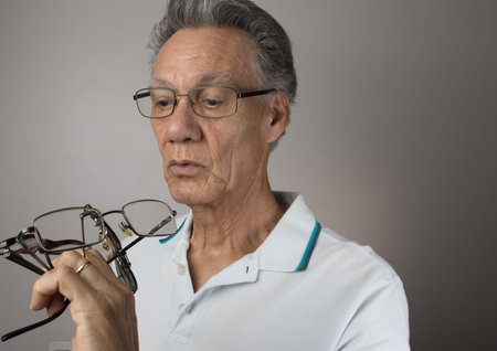 Mature Man checking out and holding up all his old prescription glassesの写真素材