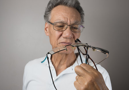 Mature Man checking out and holding up all his old prescription glassesの写真素材