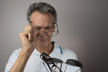 Mature Man checking out and holding up all his old prescription glassesの写真素材