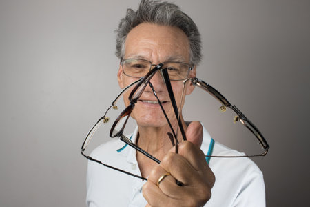 Mature Man checking out and holding up all his old prescription glassesの写真素材