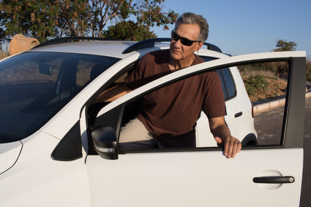 Mature Man getting out of his car on a lone country roadの写真素材