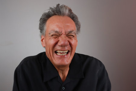 Older Mature Man against a Gray background breaking out in laughterの写真素材