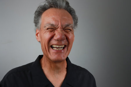 Older Mature Man against a Gray background breaking out in laughterの写真素材