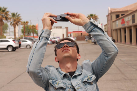 Young Man Looking at the Sun and taking photos During a Solar Eclipse using a Black Obsidian Stone