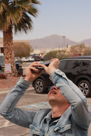 Young Man Looking at the Sun and taking photos During a Solar Eclipse
