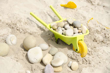 plastic wheel barrow on a sandy beachの写真素材