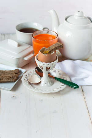 Breakfast set with boiled egg, bread and orange and carrot juiceの写真素材