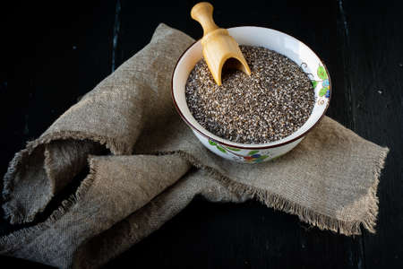 Superfood Chia seeds in ceramic bowl with wooden spoonの写真素材