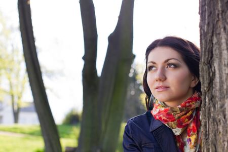 Beautiful young girl near tree in the parkの写真素材
