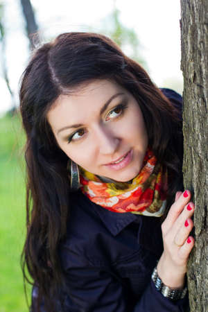 Beautiful young girl near tree in the parkの写真素材